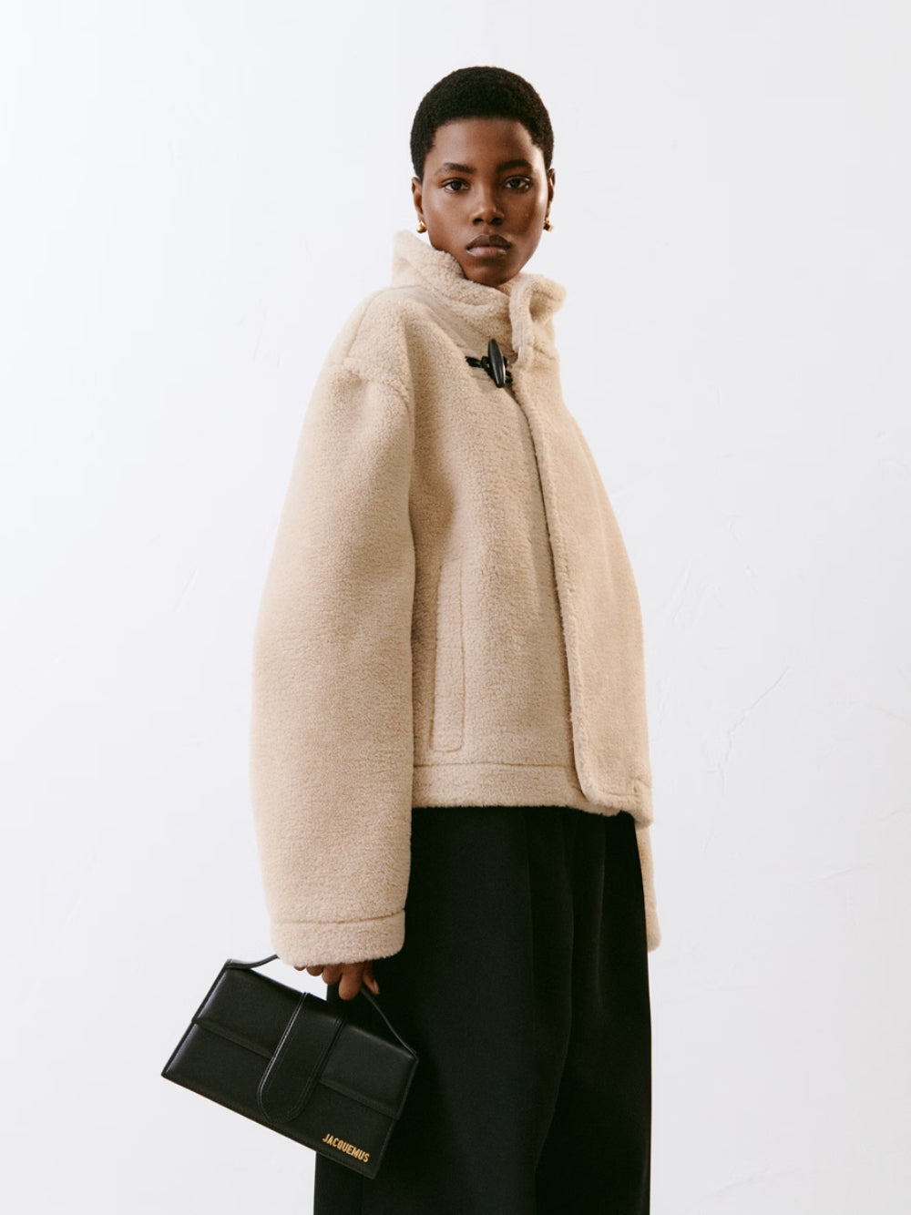Small Crossbody Flap Handbag by Jacquemus for women in leather black & gold features a transformative sophistication silhouette, showcasing a secure flap & magnetic, ample cardholder, and versatile crossbody-strap, shoulder-strap, adjustable-strap & handle for a transformative sophistication look.