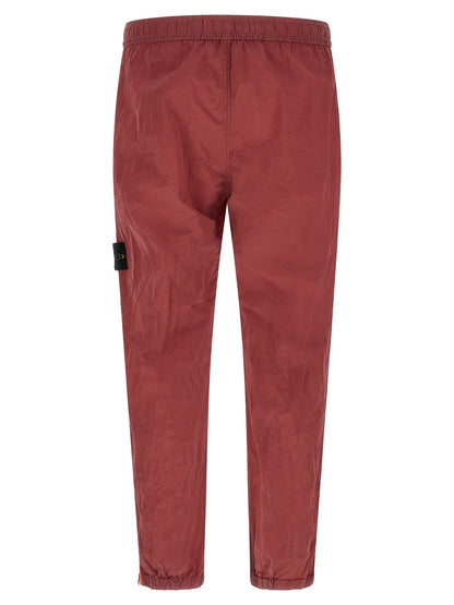 Joggers by Stone Island for men in nylon red features a polished silhouette with a polished regular-fit, reaching a polished long and finished with a polished .