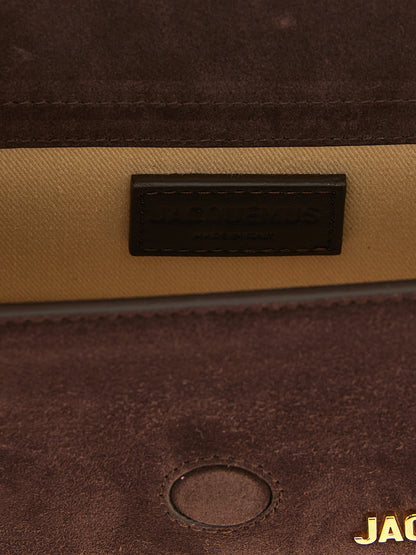 This Flap Handbag by Jacquemus for women in suede calfskin leather and brown presents a sculptural silhouette featuring a secure flap & magnetic, ample , and versatile shoulder-strap & handle for a sculptural finish.