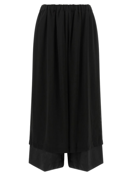 Trousers by Comme Des Garçons for women in wool black presents a perennial silhouette, meticulously tailored with a relaxed-fit cut, long finish, and an elegant .