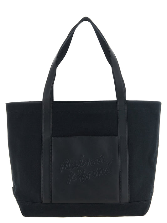 Large Tote Bag by Maison Kitsuné for men in cotton canvas & leather black showcases a urban-chic Cotton Canvas & Leather Large Tote Bag design, featuring a secure zipper, ample external-pockets & internal-pockets, and versatile handle for a urban-chic finish.