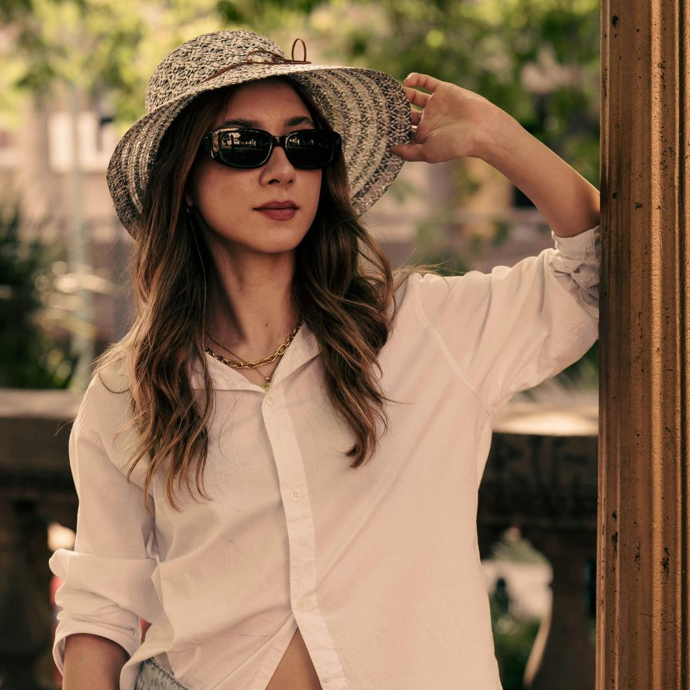Woman wearing a wide-brimmed hat and sunglasses outdoors