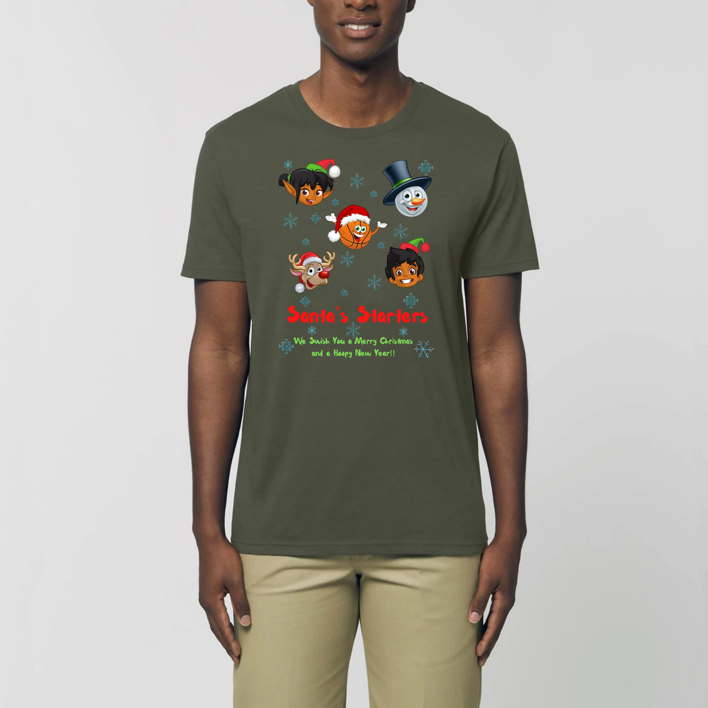 Model wearing a basketball themed Christmas t-shirt with a print design, The design features 5 cartoon character heads of 2 elves, a snowman, Rudolf and a basketball head with the heading Santa's Starters and sub heading We swish you a Merry Christmas and a Hoopy New Year. The t-shirt is Khaki