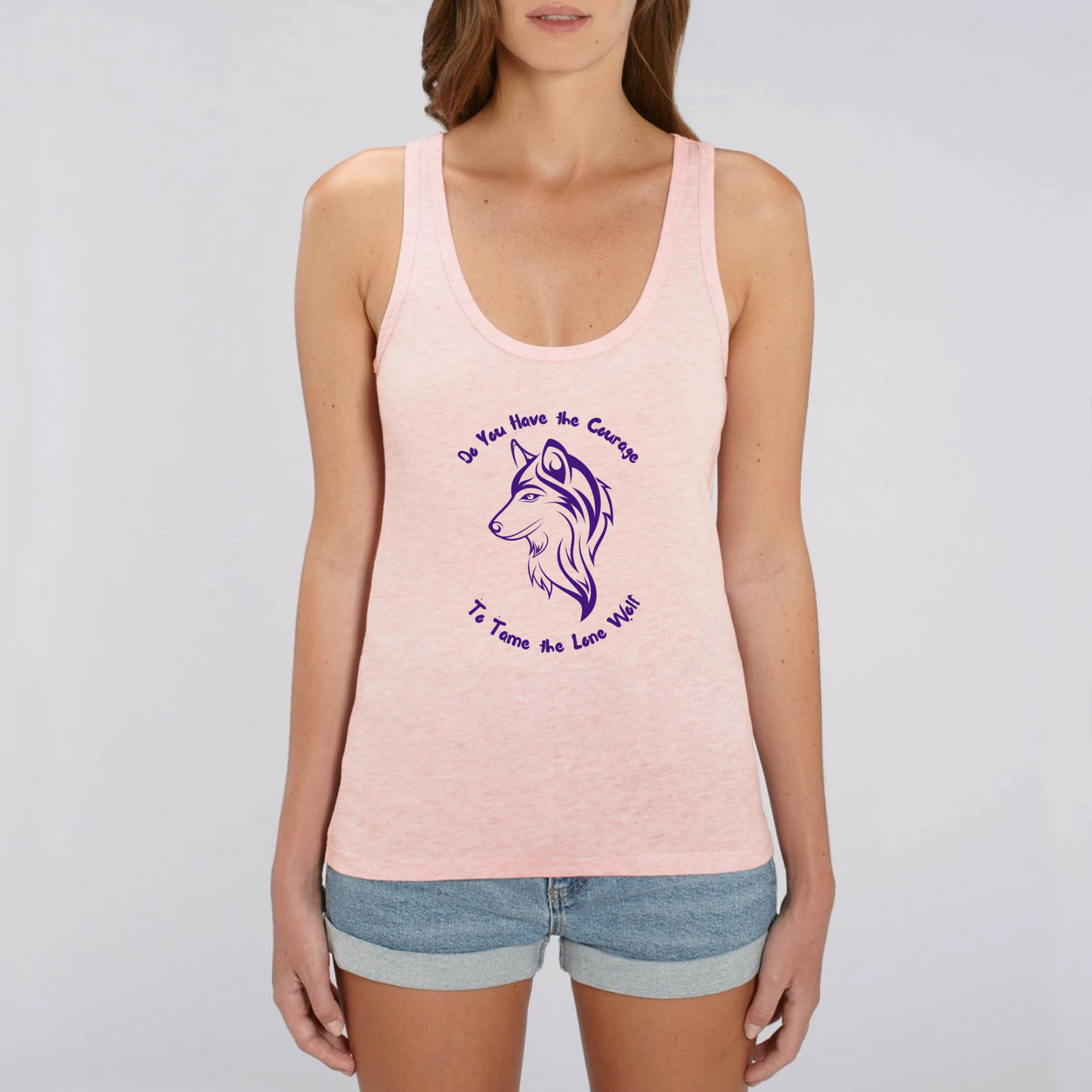 Model wearing a tank top with graphic design of a lone female wolf with wording Do you have the courage to tame the lone wolf. The tank top is pink
